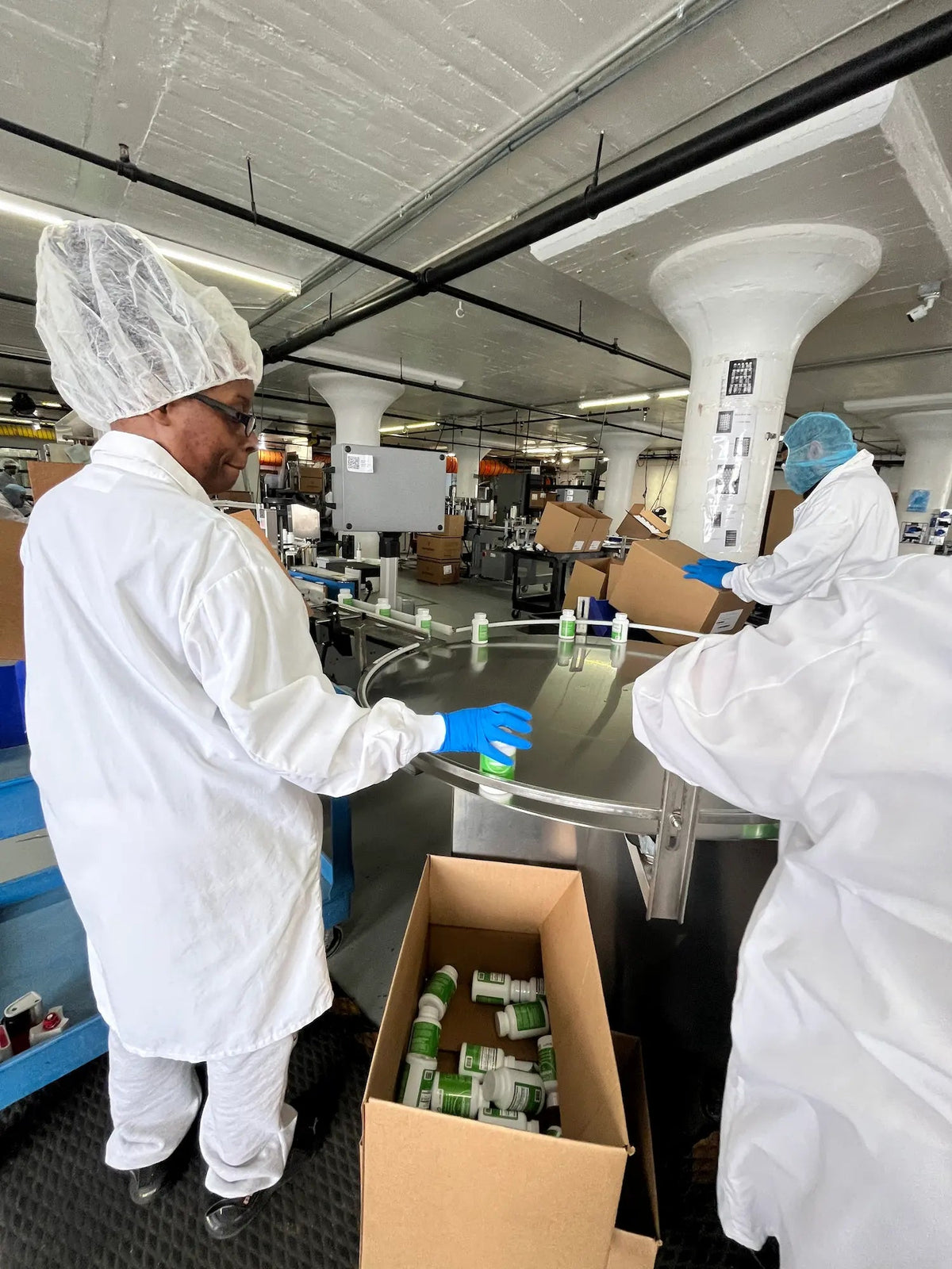 Staff in protective clothing packing Rosabella bottles at an FDA-registered facility